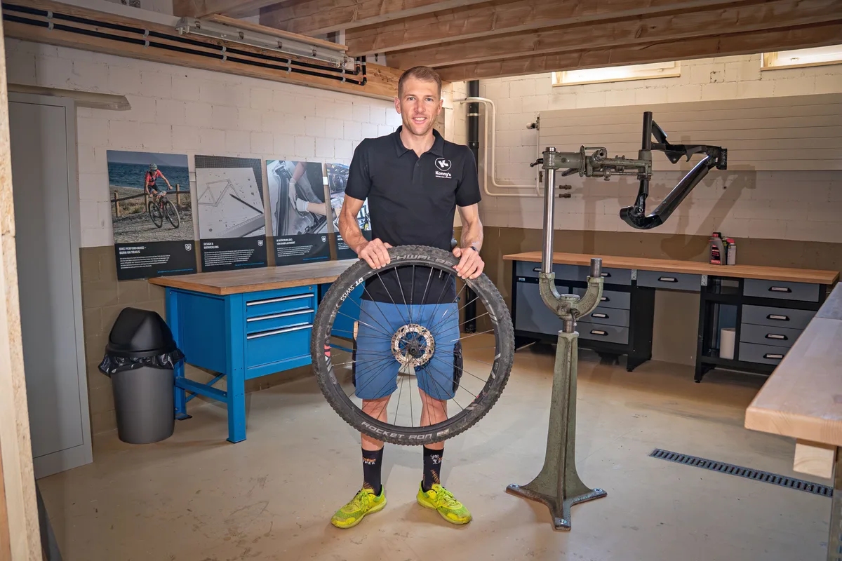 Konny Looser steht in seiner Werkstatt. In den Händen hält er das Rad eines Mountainbikes.